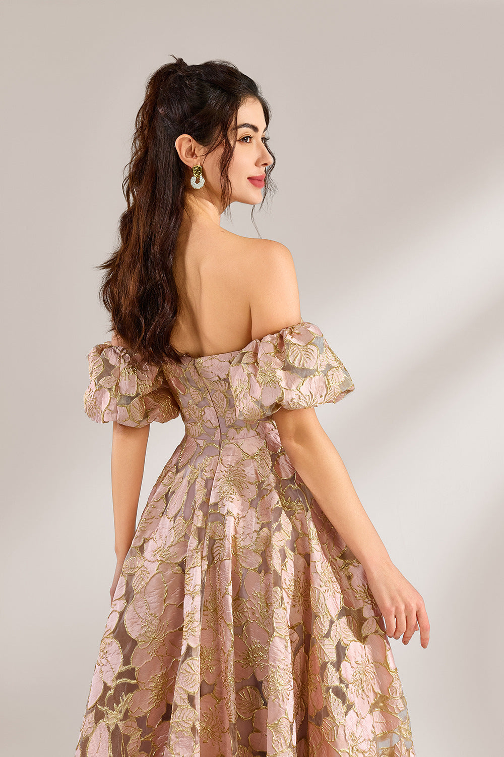 A woman with long, wavy dark hair and a poised stance wears a light - pink, floral - embroidered off - the - shoulder gown. It has puffed sleeves, a fitted bodice, and a voluminous skirt. Paired with understated heels, the outfit radiates elegance, perfect for formal events like galas or weddings.5