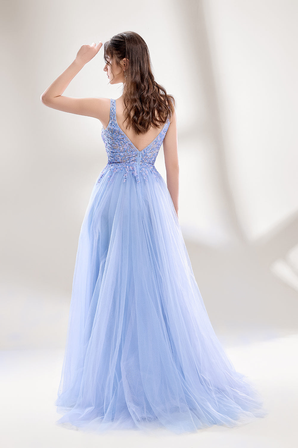 Bathed in soft light, a woman dazzles in a light blue tulle gown. It has a deep V - neckline with delicate lace embroidery on the bodice, and a flowing tulle skirt. The ethereal design creates a romantic and dreamy look, perfect for formal events like proms or weddings.2