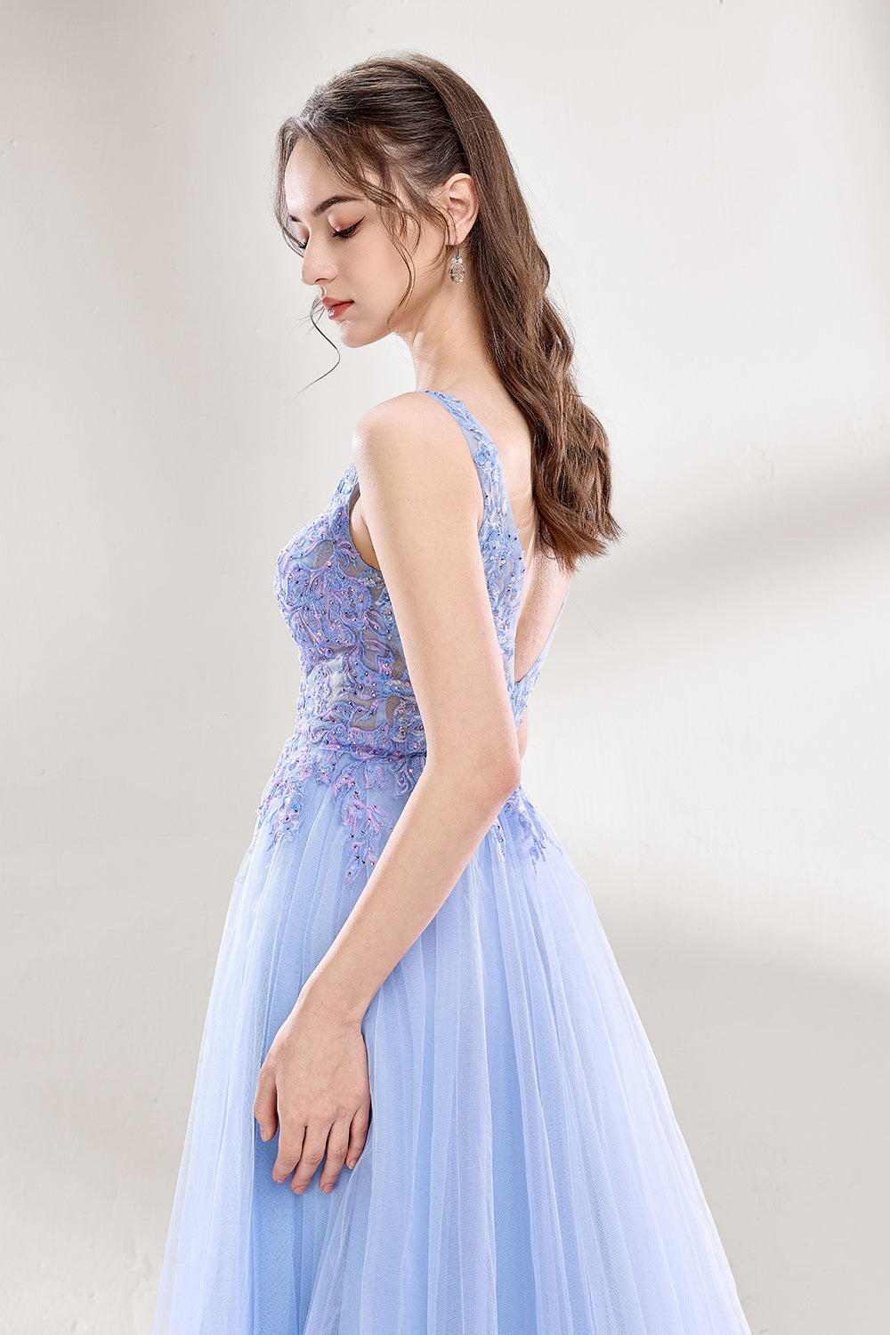 Bathed in soft light, a woman dazzles in a light blue tulle gown. It has a deep V - neckline with delicate lace embroidery on the bodice, and a flowing tulle skirt. The ethereal design creates a romantic and dreamy look, perfect for formal events like proms or weddings.3