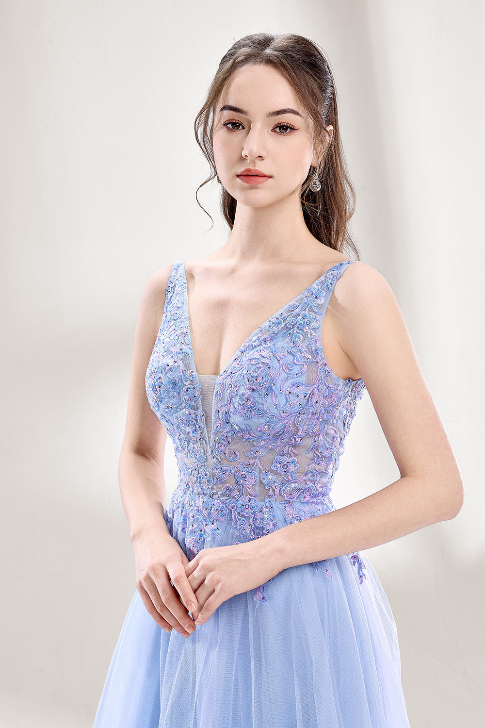 Bathed in soft light, a woman dazzles in a light blue tulle gown. It has a deep V - neckline with delicate lace embroidery on the bodice, and a flowing tulle skirt. The ethereal design creates a romantic and dreamy look, perfect for formal events like proms or weddings.6