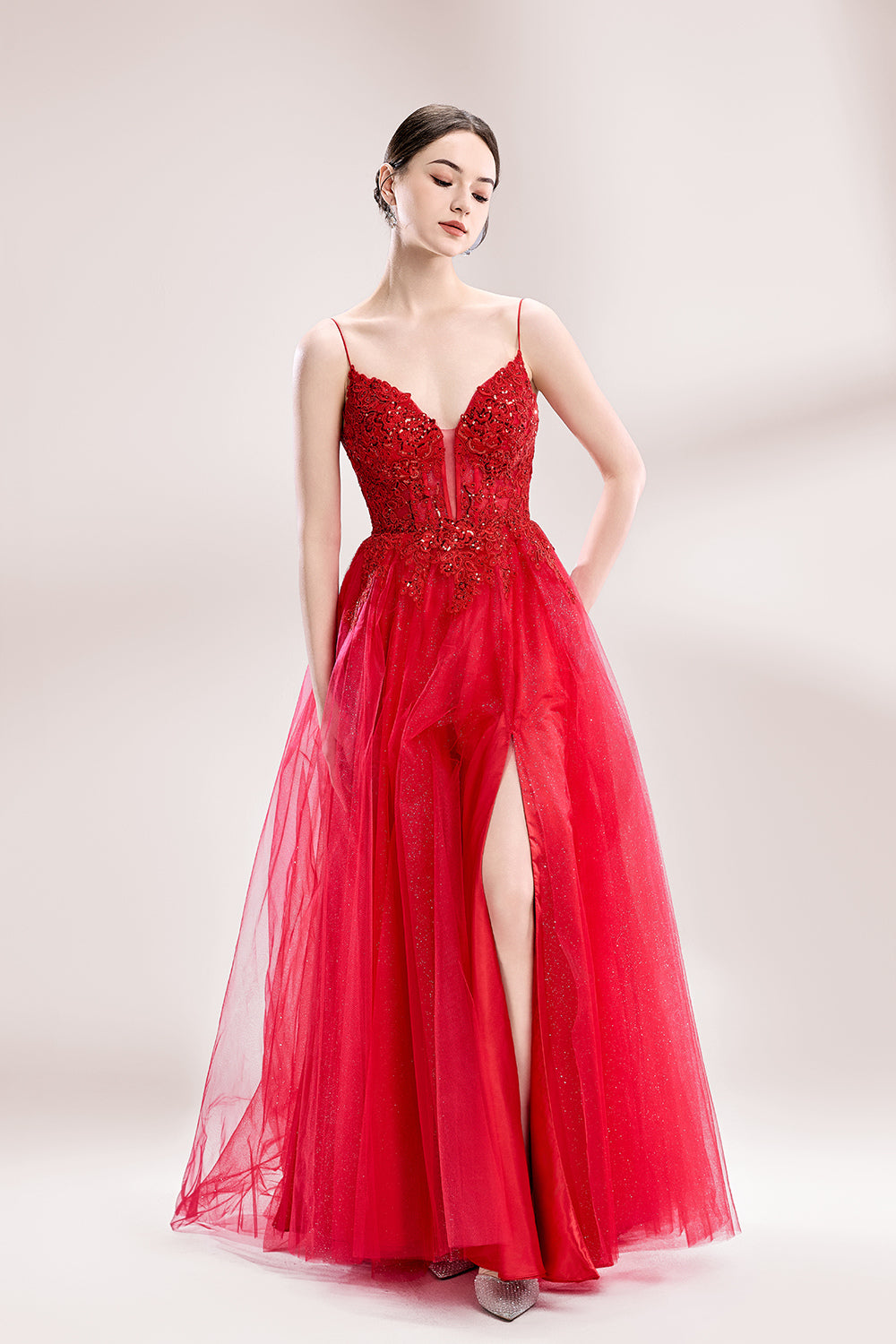 A woman stands against a light background, wearing a red tulle gown. It features thin straps, a deep V - neckline, intricate lace embroidery with sequins on the bodice, and a high side slit. The voluminous tulle skirt creates a romantic and glamorous look, perfect for formal events like proms or weddings.6