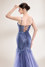 Photograph of a young Asian woman with fair skin and dark hair in a sleek bun, wearing a stunning, floor-length, deep blue evening gown. The gown has a plunging V-neckline, adorned with intricate beading and sequins, and features a sheer overlay with a high slit on one side, revealing a layer of tulle. The background is a soft, neutral gradient, highlighting the gown's elegance. She accessorizes with large, dangling earrings.6