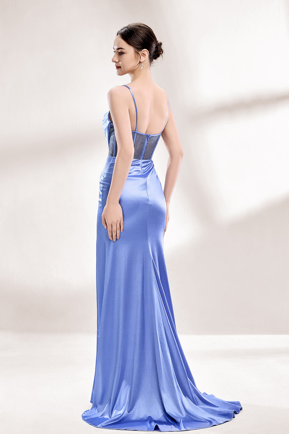 A woman with sleek dark hair and a poised stance wears a light - blue satin gown. It has thin straps, a cowl neckline, sheer mesh side panels, and a high side slit. Paired with understated earrings, the outfit radiates elegance, perfect for formal events like galas or evening receptions.56