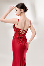 A woman with sleek dark hair and a poised stance wears a red, glittery gown. It has thin straps, beaded bodice, and a high side slit. Paired with silver heels, the outfit radiates elegance, perfect for formal events like galas, blending glamour and style.
3