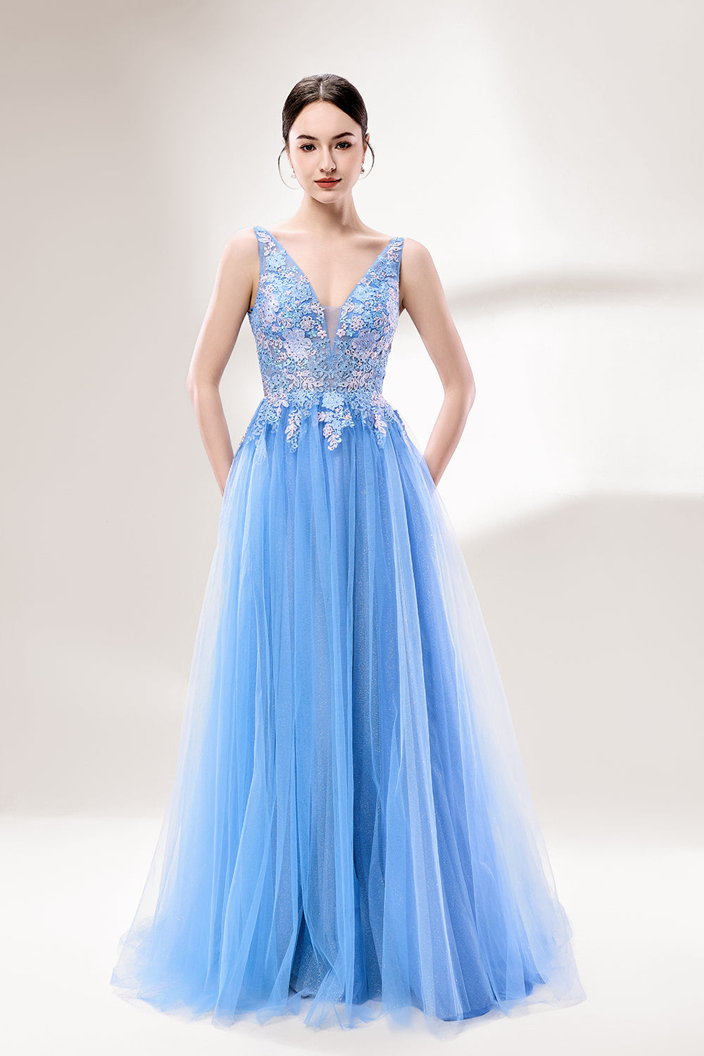 Bathed in soft light, a woman stands out in a light blue tulle gown. It has a deep V - neckline with delicate lace embroidery on the bodice, and a flowing tulle skirt. The ethereal design creates a romantic and dreamy look, perfect for formal events like proms or weddings.1