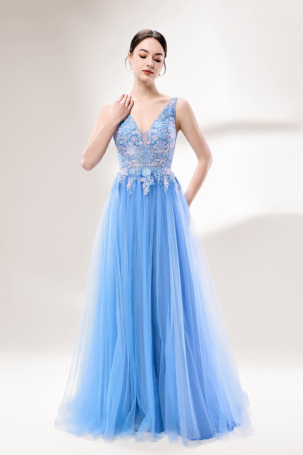 Bathed in soft light, a woman stands out in a light blue tulle gown. It has a deep V - neckline with delicate lace embroidery on the bodice, and a flowing tulle skirt. The ethereal design creates a romantic and dreamy look, perfect for formal events like proms or weddings.3