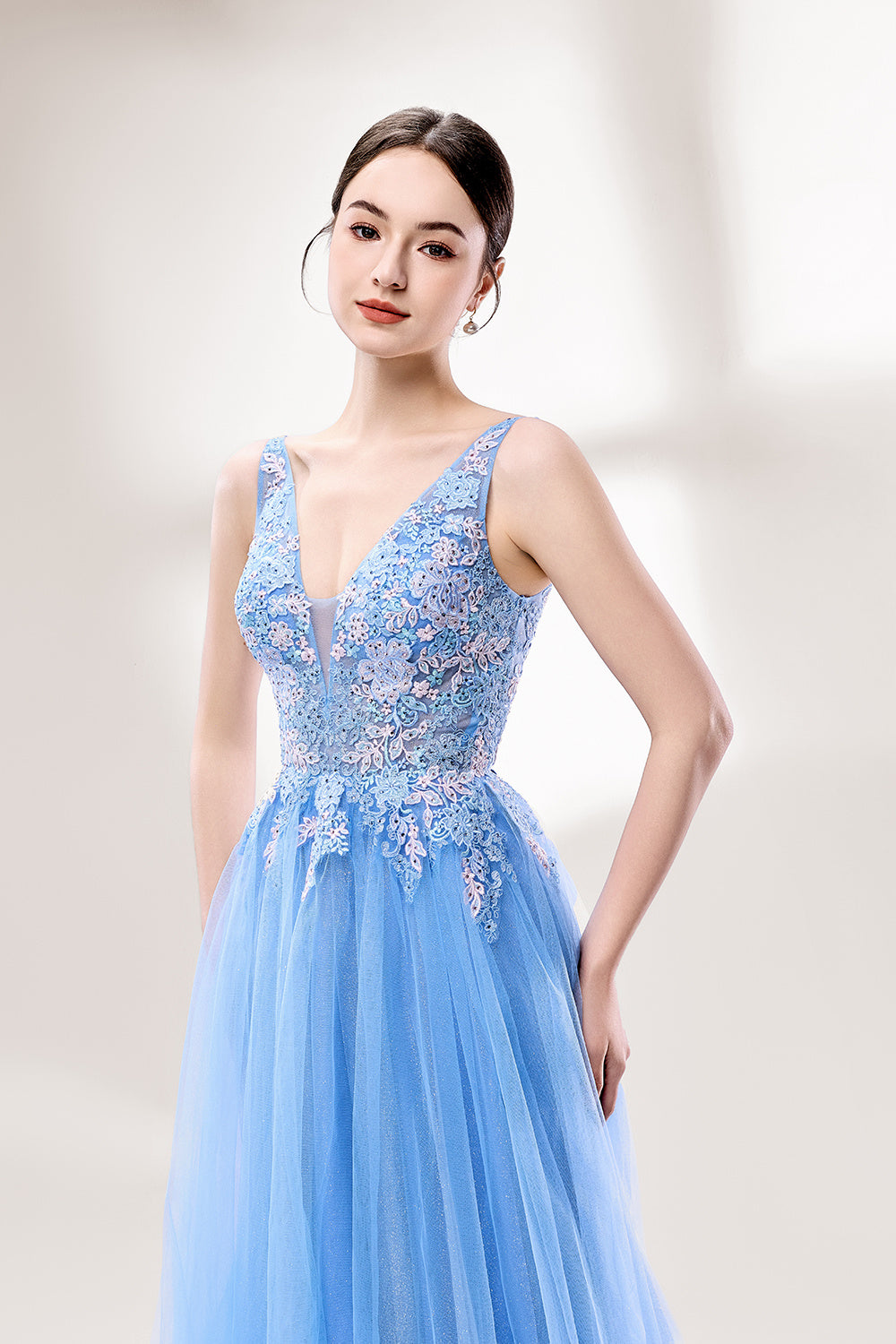 Bathed in soft light, a woman stands out in a light blue tulle gown. It has a deep V - neckline with delicate lace embroidery on the bodice, and a flowing tulle skirt. The ethereal design creates a romantic and dreamy look, perfect for formal events like proms or weddings.4