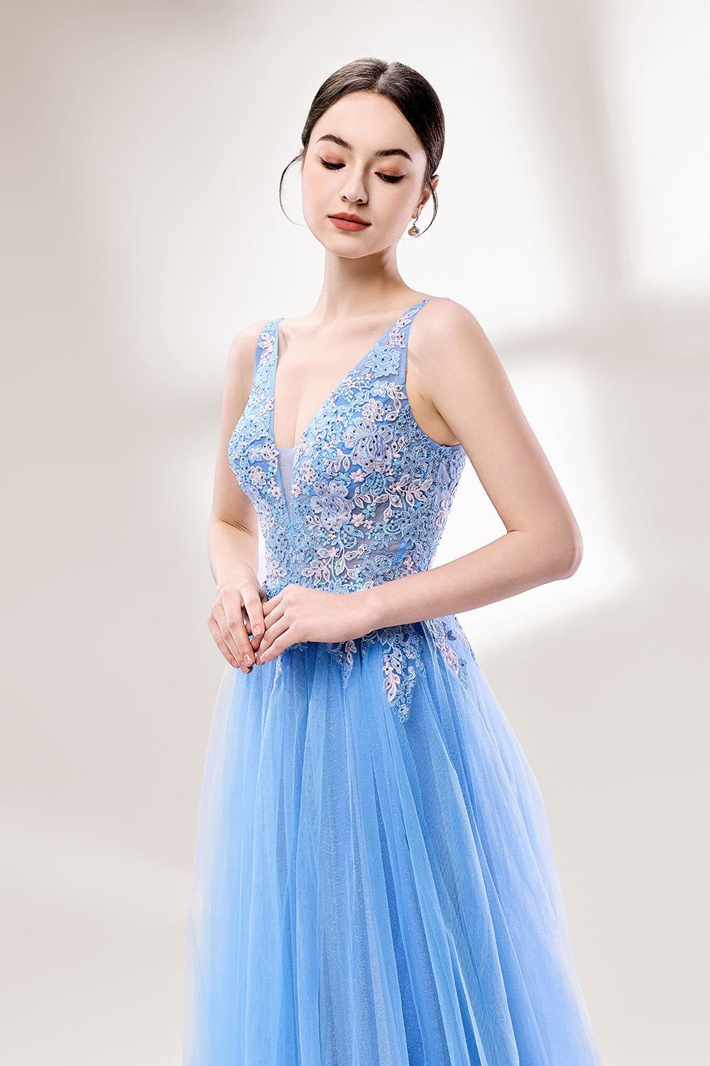 Bathed in soft light, a woman stands out in a light blue tulle gown. It has a deep V - neckline with delicate lace embroidery on the bodice, and a flowing tulle skirt. The ethereal design creates a romantic and dreamy look, perfect for formal events like proms or weddings.5