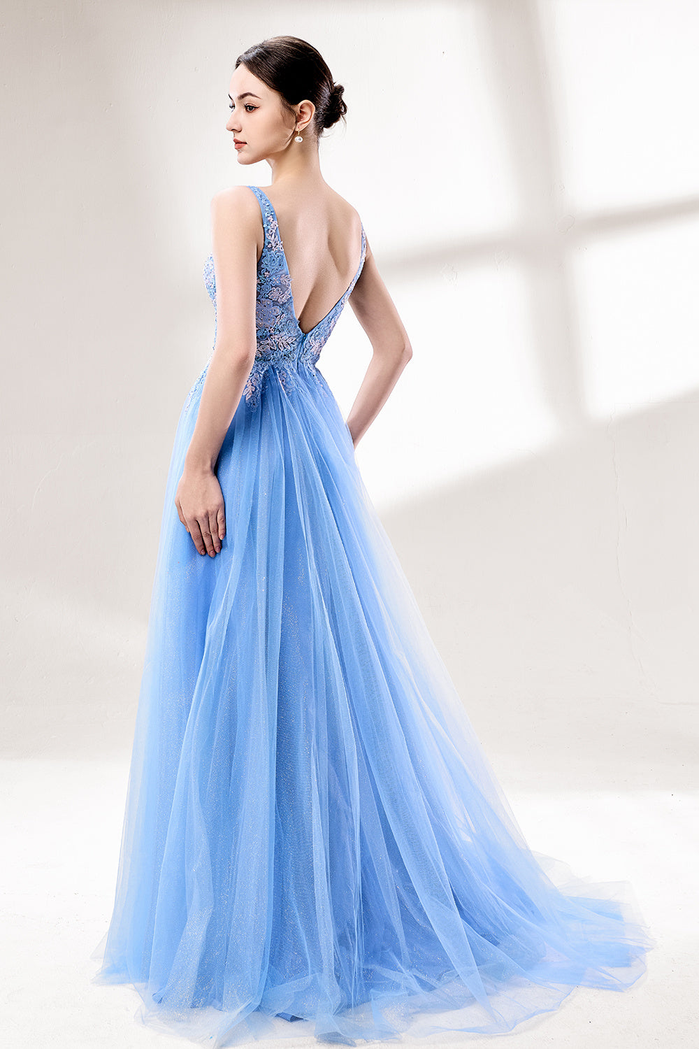 Bathed in soft light, a woman stands out in a light blue tulle gown. It has a deep V - neckline with delicate lace embroidery on the bodice, and a flowing tulle skirt. The ethereal design creates a romantic and dreamy look, perfect for formal events like proms or weddings.2