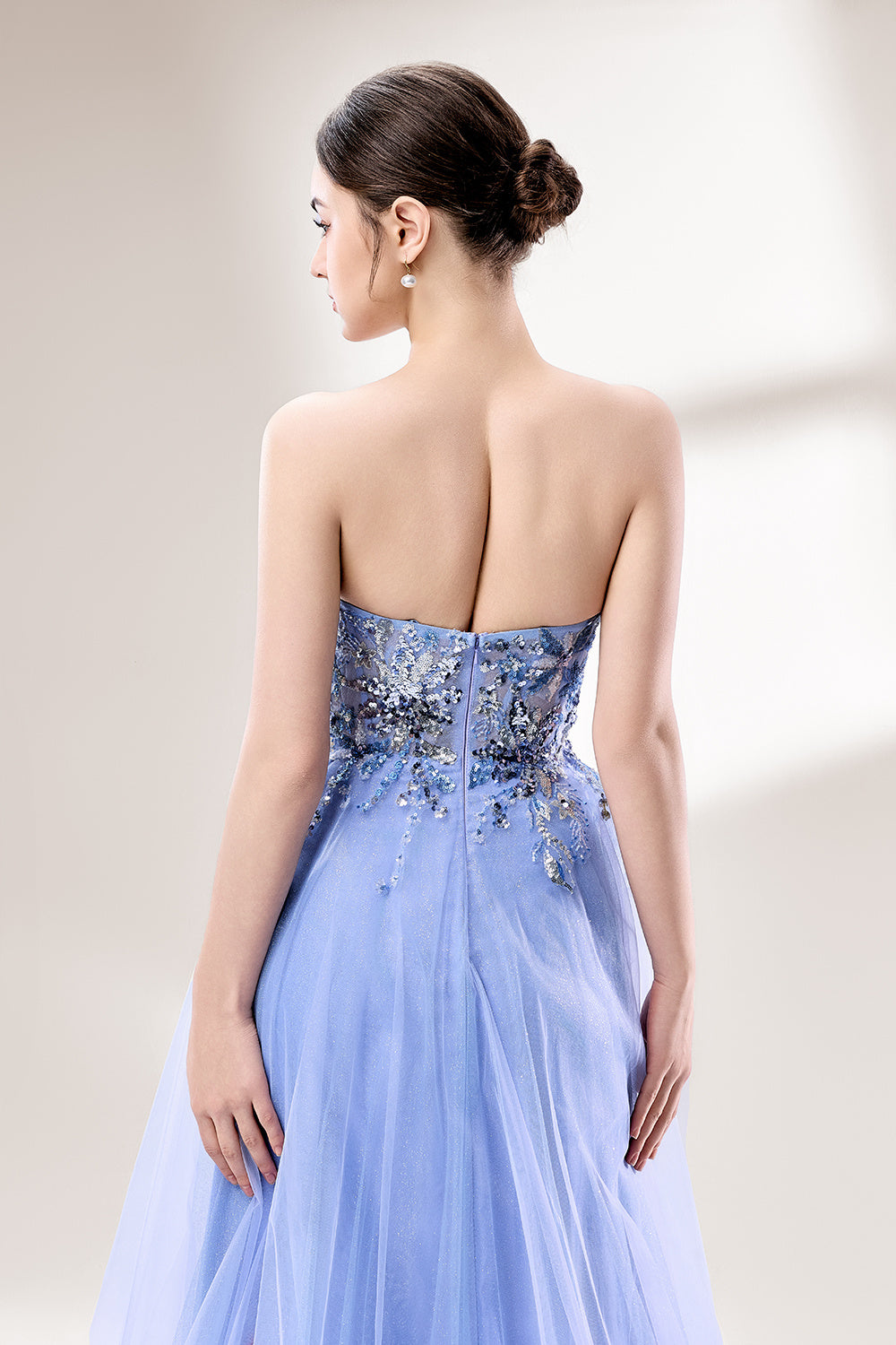 Set against a light background, a woman wears a light blue strapless ball gown. It features a sweetheart neckline with intricate floral beadwork on the bodice, and a voluminous tulle skirt. The elegant design creates a romantic and dreamy look, perfect for formal events like proms or weddings.6