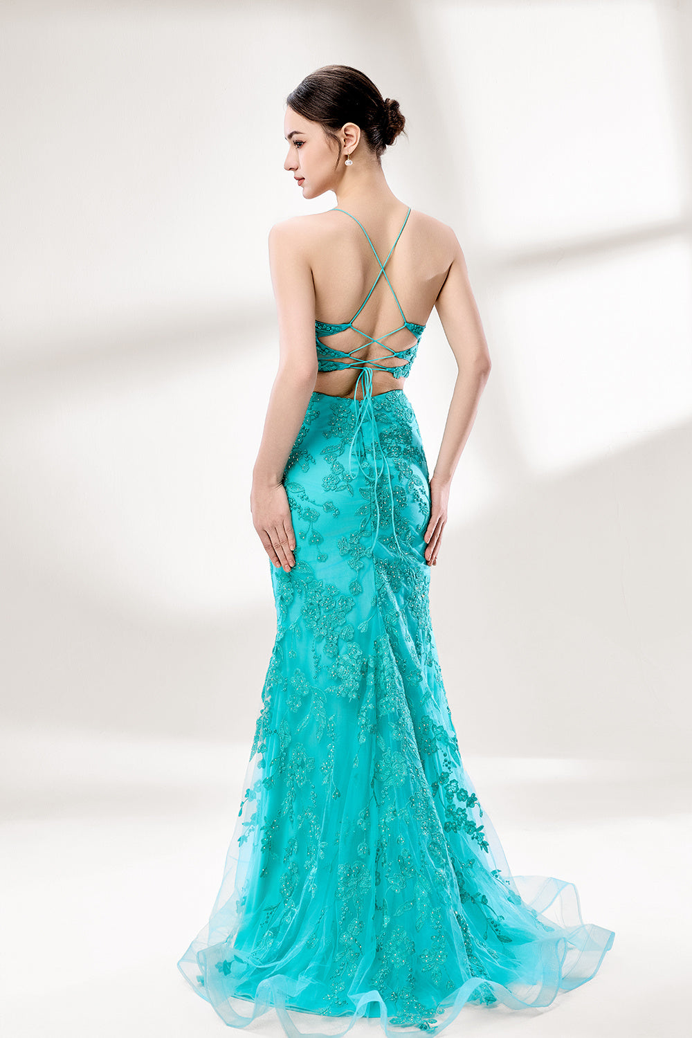 Set against a light background, a woman dons a turquoise tulle gown adorned with floral lace. It has thin straps, a sweetheart neckline, and a mermaid - shaped skirt with a high side slit. The delicate lace and flowing fabric exude romance, ideal for weddings or formal dinners.2