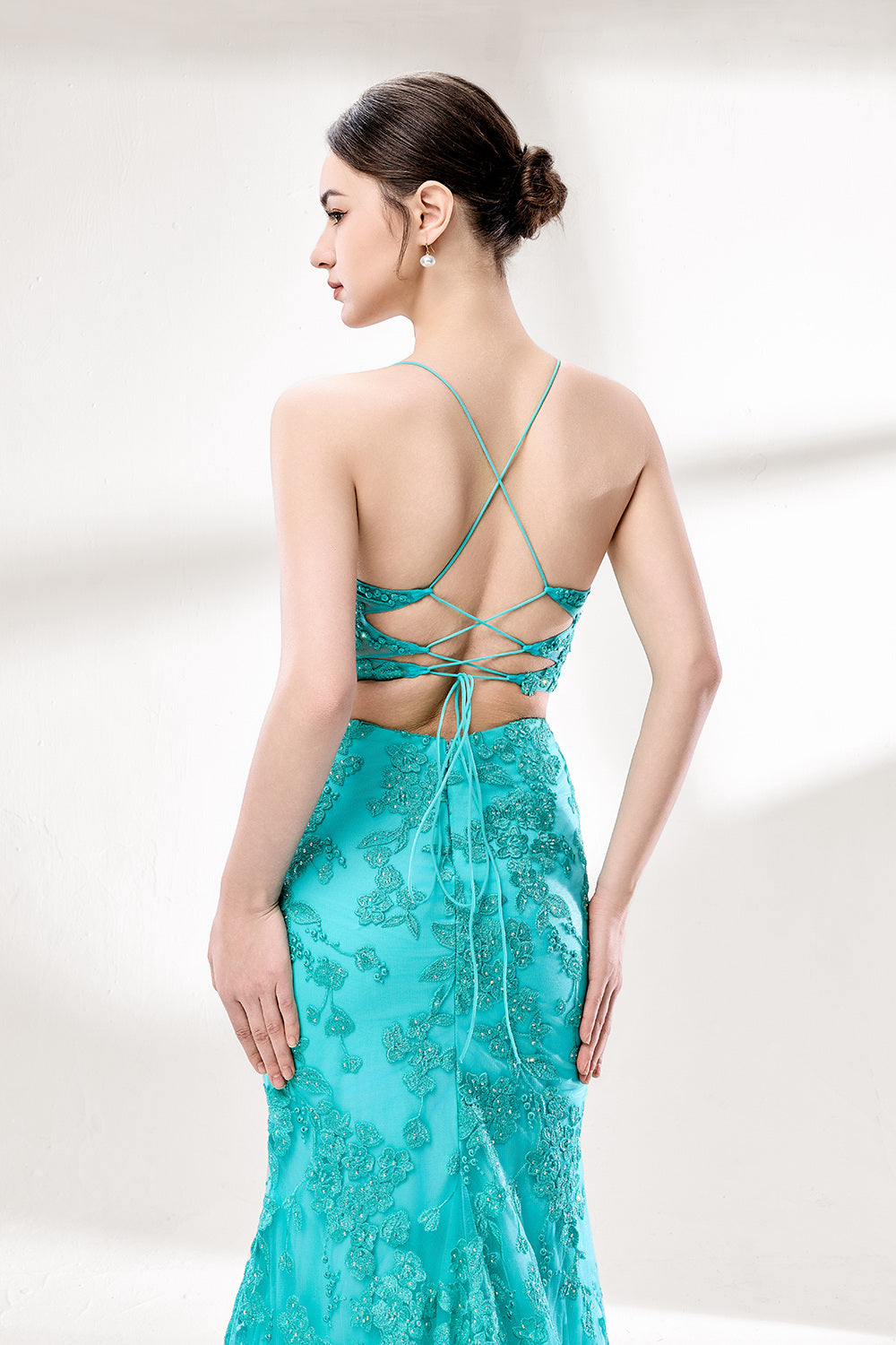 Set against a light background, a woman dons a turquoise tulle gown adorned with floral lace. It has thin straps, a sweetheart neckline, and a mermaid - shaped skirt with a high side slit. The delicate lace and flowing fabric exude romance, ideal for weddings or formal dinners.