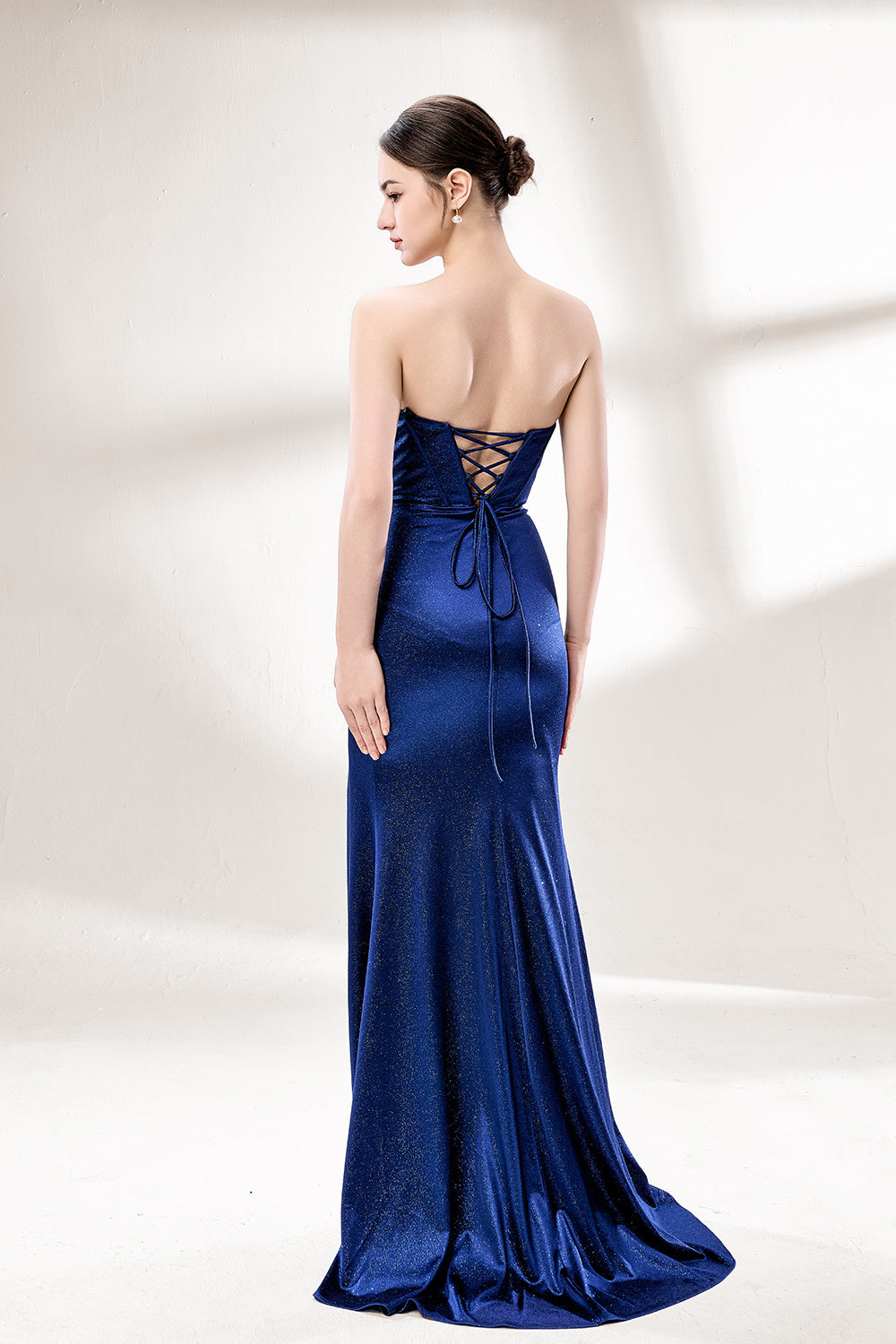 This is a strapless royal - blue gown. It features a twisted - front design at the bustline, with a sheer panel in the middle of the bodice. The waist is cinched with ruched detailing, and the skirt is mermaid - shaped with a high side slit. Paired with silver - glittered heels, it exudes elegance and sensuality, perfect for formal events like galas or balls.2