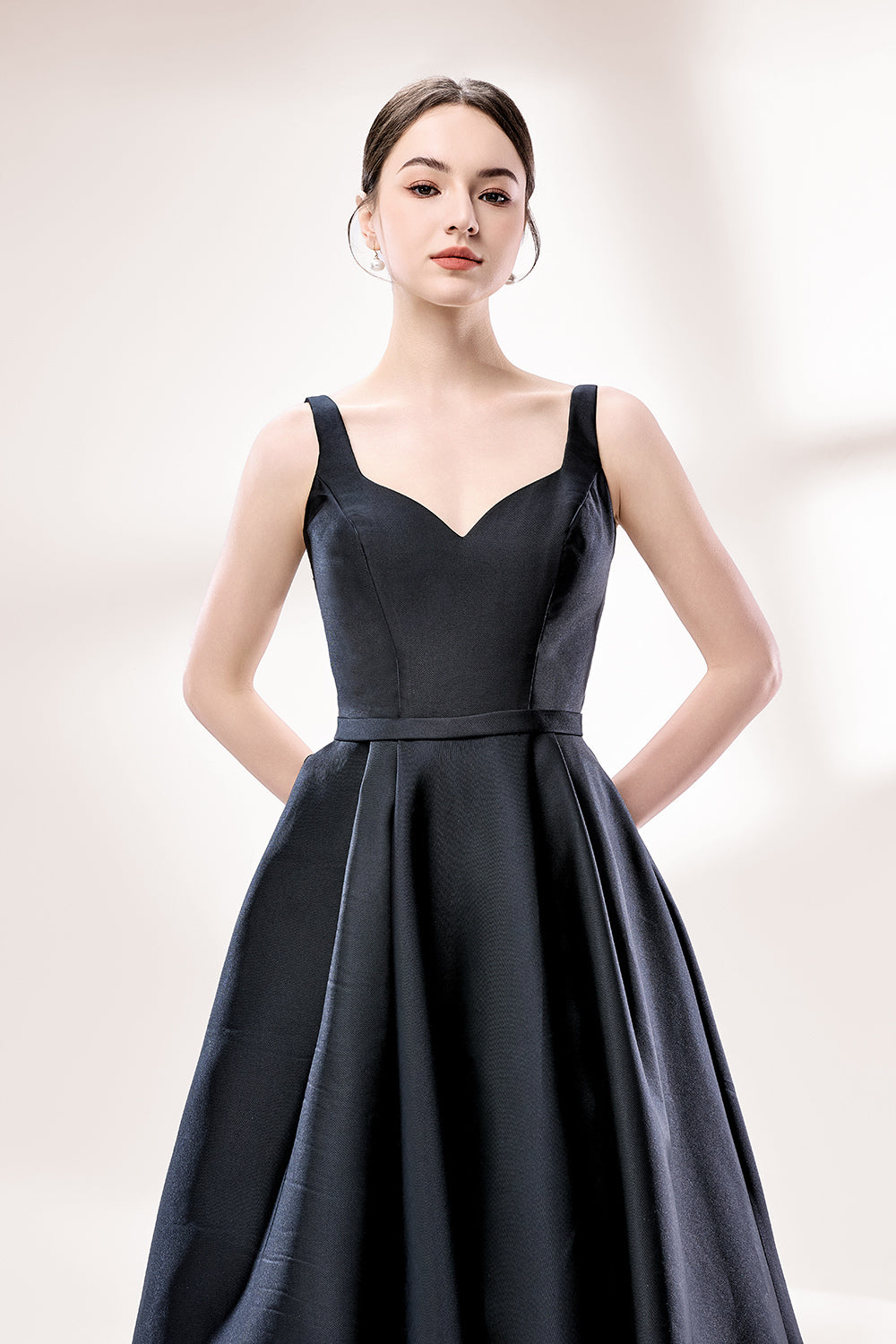 A woman stands against a light background, wearing a black satin gown. It features thin straps, a V - neckline, and a high side slit. The smooth satin fabric and elegant silhouette exude sophistication, perfect for formal events like galas or charity balls, radiating timeless charm.6