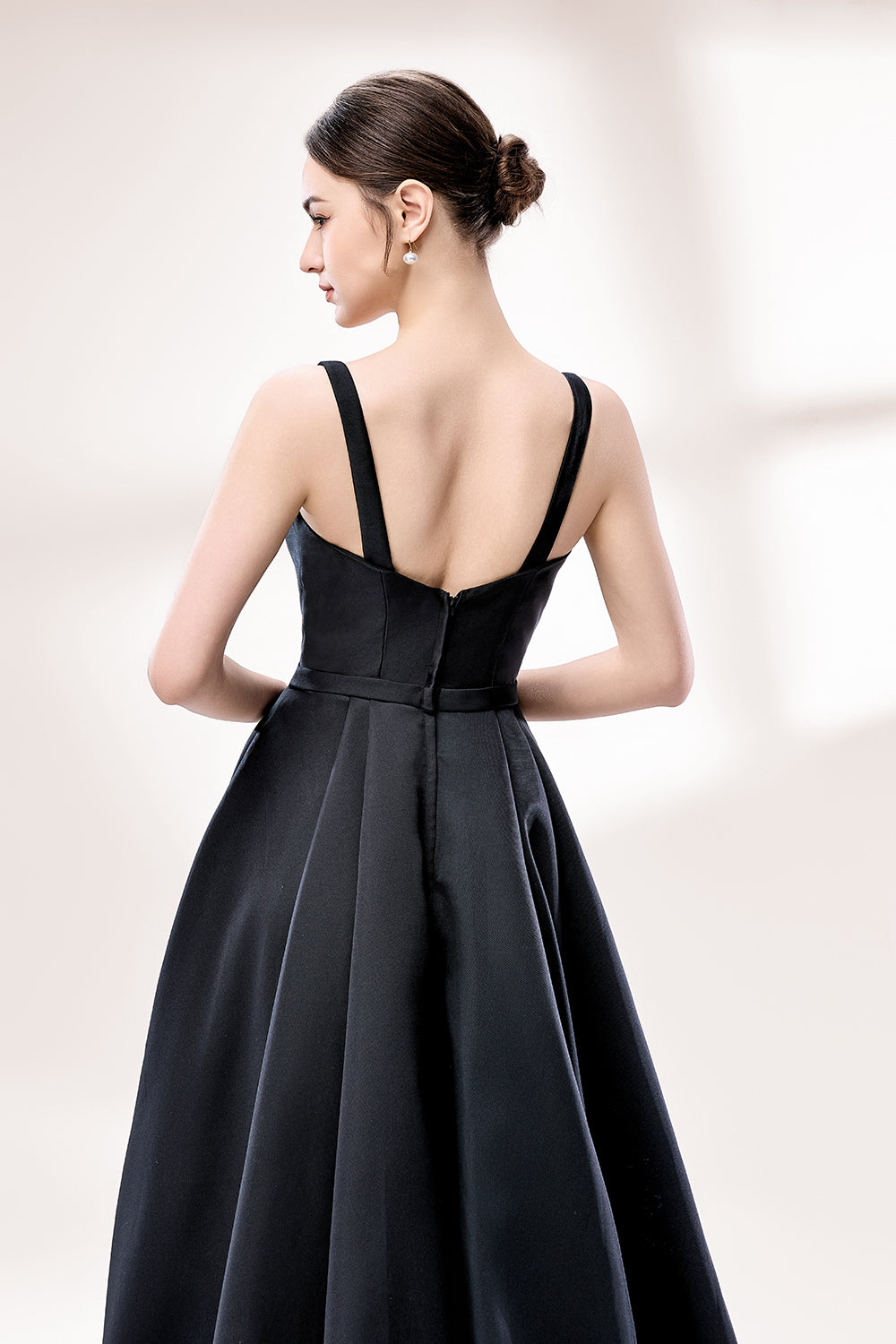 A woman stands against a light background, wearing a black satin gown. It features thin straps, a V - neckline, and a high side slit. The smooth satin fabric and elegant silhouette exude sophistication, perfect for formal events like galas or charity balls, radiating timeless charm.5