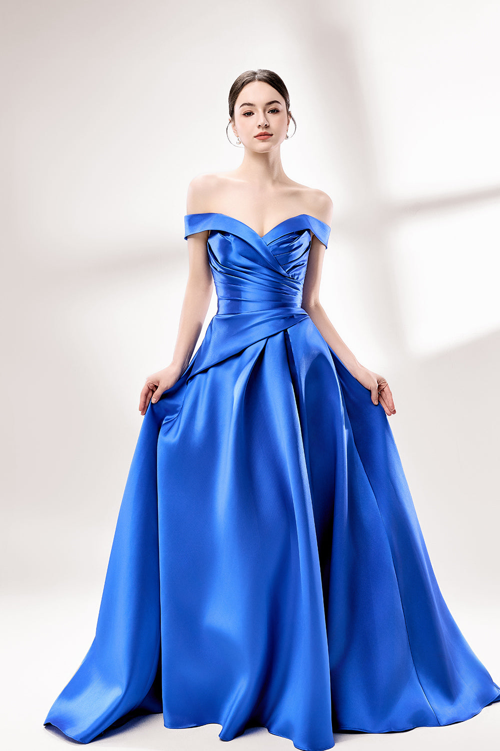 Set against a light backdrop, a woman dons a royal - blue satin gown with an off - shoulder neckline and a high side slit. It has a ruched bodice and pockets, combining elegance and practicality. The shiny satin fabric creates a glamorous look, ideal for proms or formal evening gatherings.3