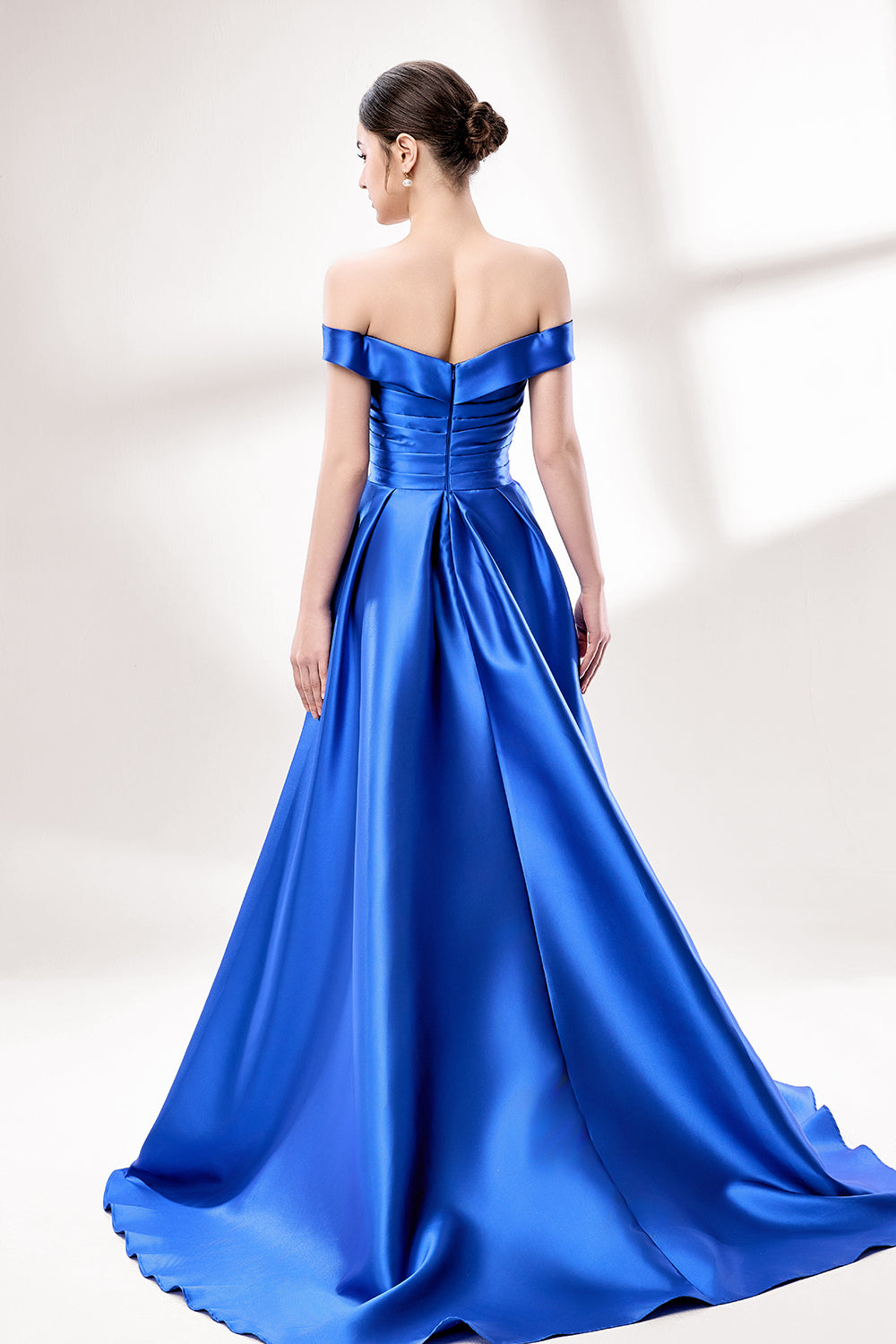 Set against a light backdrop, a woman dons a royal - blue satin gown with an off - shoulder neckline and a high side slit. It has a ruched bodice and pockets, combining elegance and practicality. The shiny satin fabric creates a glamorous look, ideal for proms or formal evening gatherings.2
