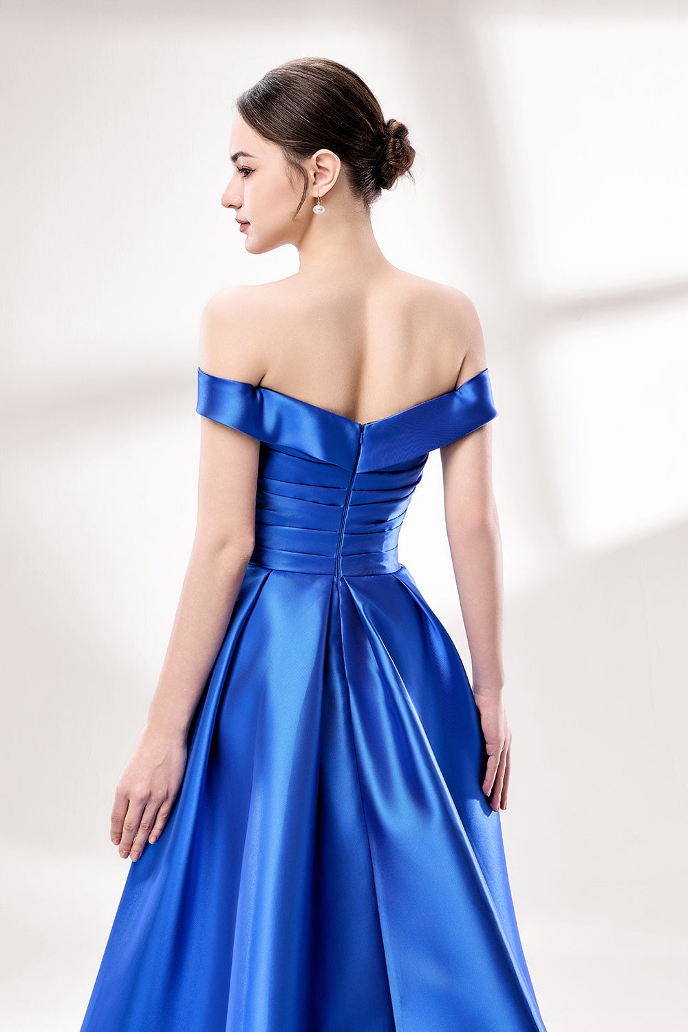 Set against a light backdrop, a woman dons a royal - blue satin gown with an off - shoulder neckline and a high side slit. It has a ruched bodice and pockets, combining elegance and practicality. The shiny satin fabric creates a glamorous look, ideal for proms or formal evening gatherings.6