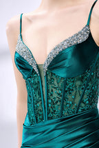 Set against a light background, a woman wears a teal satin gown with a bejeweled, sheer bodice. It has thin straps, a sweetheart neckline, and a mermaid - shaped skirt with a high side slit. The sparkling embellishments and smooth satin fabric exude elegance, ideal for galas or formal dinners.6
