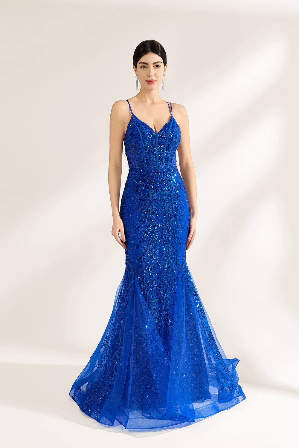 A woman stands against a light background, wearing a royal - blue, sequin - adorned mermaid gown. It features thin straps, a deep V - neckline, and a sheer tulle overlay. The sparkling sequins and figure - hugging silhouette create a glamorous look, perfect for formal events like galas or proms, exuding elegance and charm.1