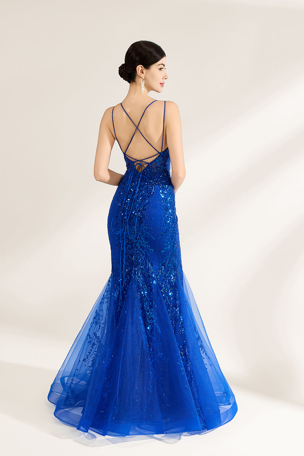 A woman stands against a light background, wearing a royal - blue, sequin - adorned mermaid gown. It features thin straps, a deep V - neckline, and a sheer tulle overlay. The sparkling sequins and figure - hugging silhouette create a glamorous look, perfect for formal events like galas or proms, exuding elegance and charm.2