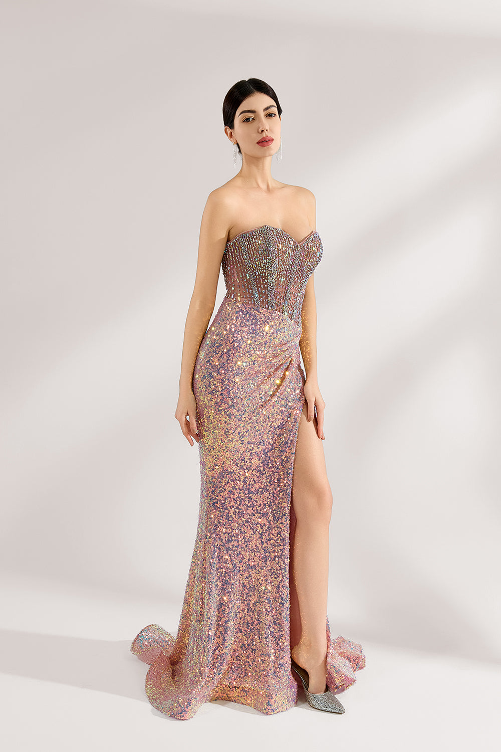 A woman with sleek dark hair and a confident stance wears a multi - colored, sequined strapless gown. It has a form - fitting silhouette, a high side slit, and bead - detailed bodice. Paired with silver heels, the outfit radiates glamour, perfect for formal events like galas or award ceremonies.3