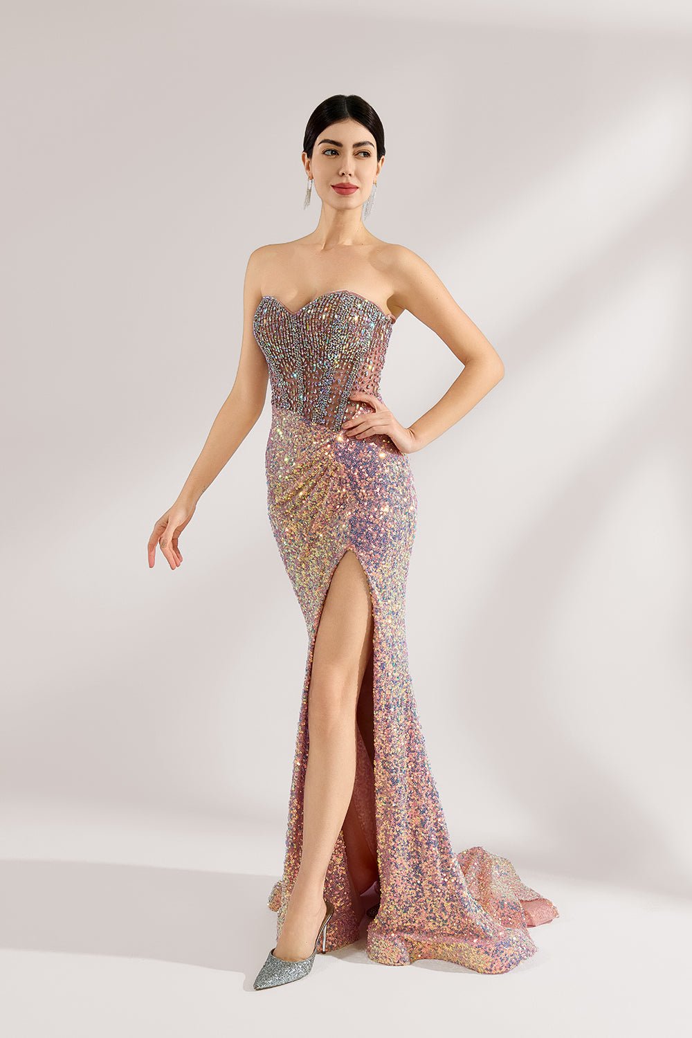 A woman with sleek dark hair and a confident stance wears a multi - colored, sequined strapless gown. It has a form - fitting silhouette, a high side slit, and bead - detailed bodice. Paired with silver heels, the outfit radiates glamour, perfect for formal events like galas or award ceremonies.4