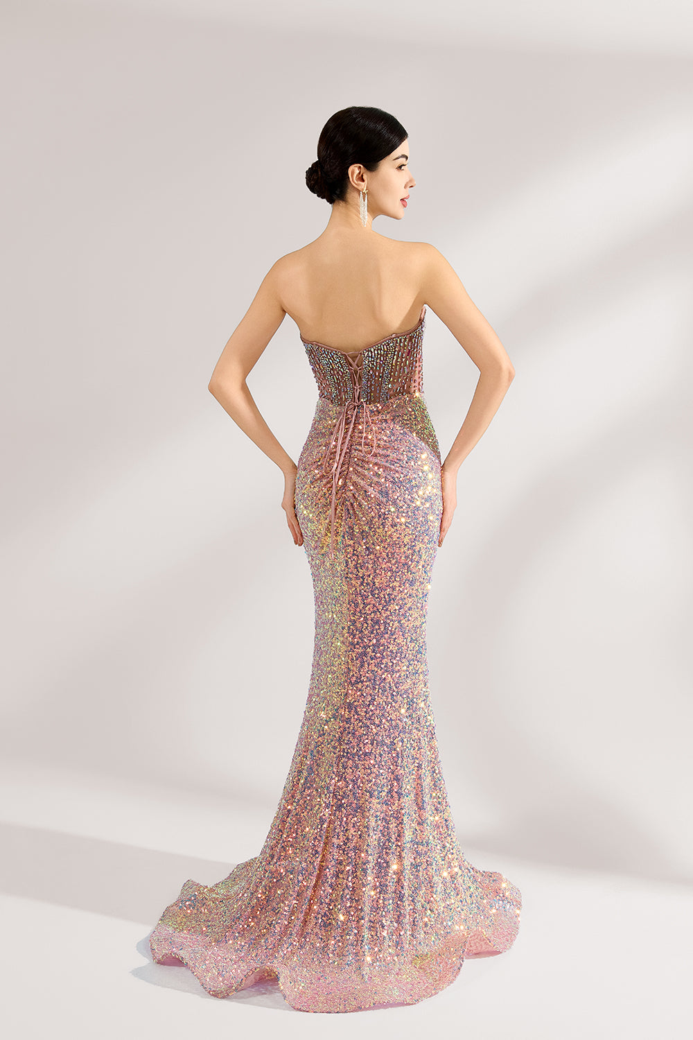 A woman with sleek dark hair and a confident stance wears a multi - colored, sequined strapless gown. It has a form - fitting silhouette, a high side slit, and bead - detailed bodice. Paired with silver heels, the outfit radiates glamour, perfect for formal events like galas or award ceremonies.2