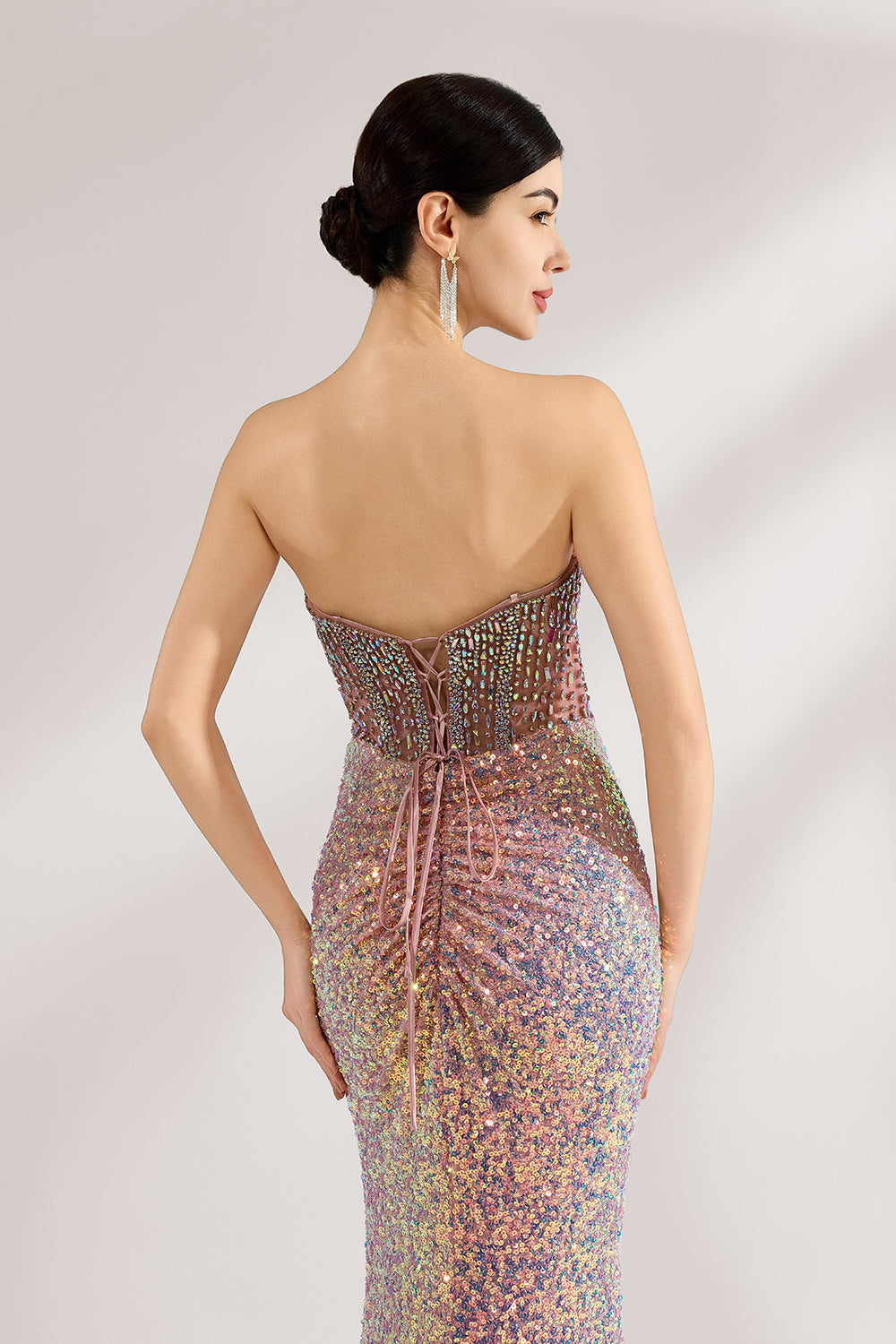 A woman with sleek dark hair and a confident stance wears a multi - colored, sequined strapless gown. It has a form - fitting silhouette, a high side slit, and bead - detailed bodice. Paired with silver heels, the outfit radiates glamour, perfect for formal events like galas or award ceremonies.6