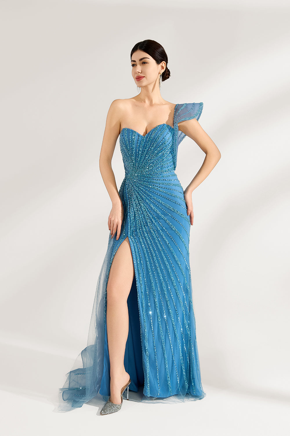 Bathed in soft light, a woman radiates elegance in a blue evening gown. With one - shoulder design, sequin detailing, and a high slit, it crafts a glamorous and sophisticated look for formal events.4