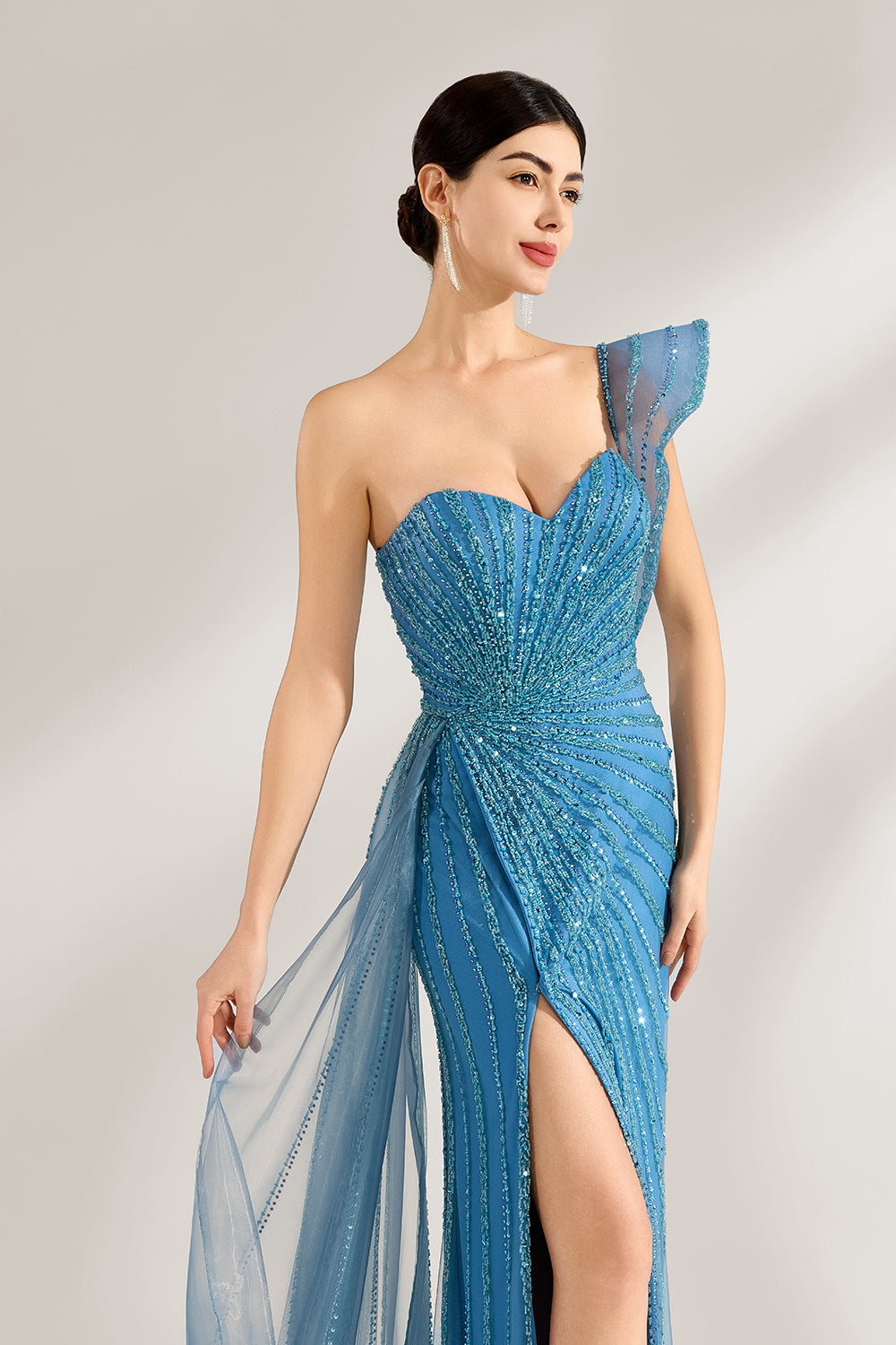 Bathed in soft light, a woman radiates elegance in a blue evening gown. With one - shoulder design, sequin detailing, and a high slit, it crafts a glamorous and sophisticated look for formal events.3