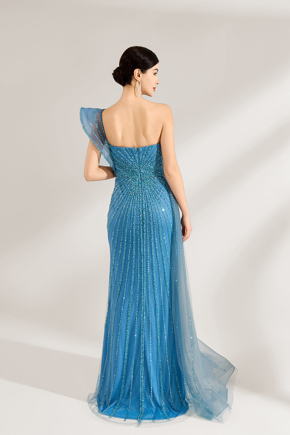 Bathed in soft light, a woman radiates elegance in a blue evening gown. With one - shoulder design, sequin detailing, and a high slit, it crafts a glamorous and sophisticated look for formal events.2