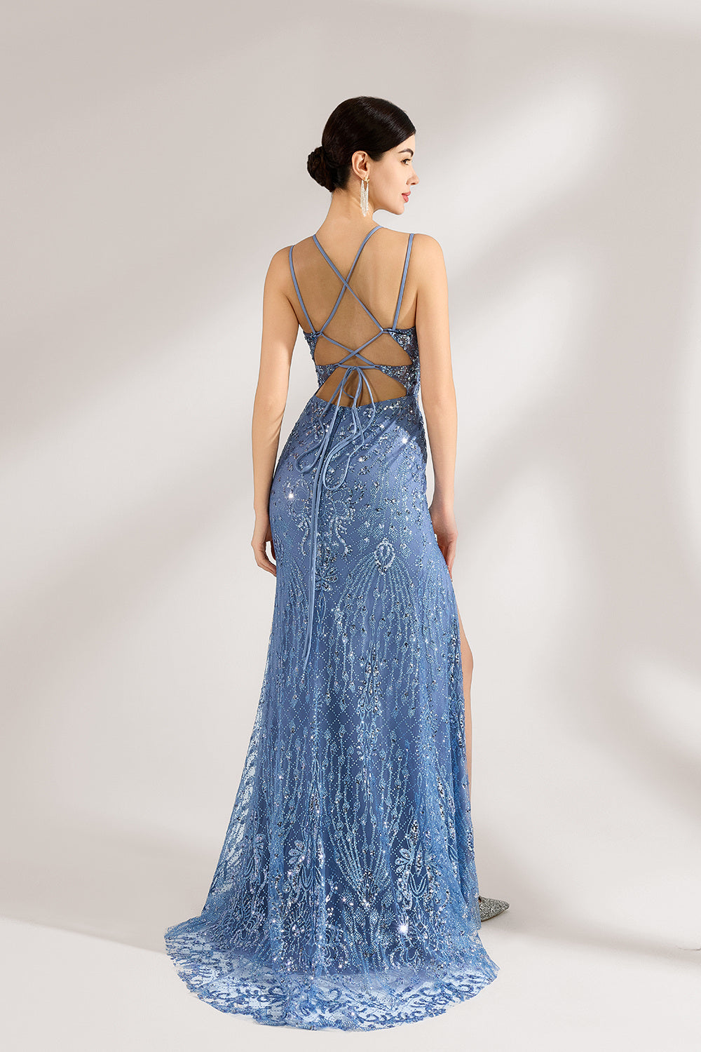 Bathed in soft light, a woman stuns in a blue mermaid - cut gown. It has thin criss - cross straps, a deep V - neckline, and is covered with intricate sequin embroidery, plus a high side slit. The shimmering details lend an air of opulence, perfect for grand galas or red - carpet moments.2