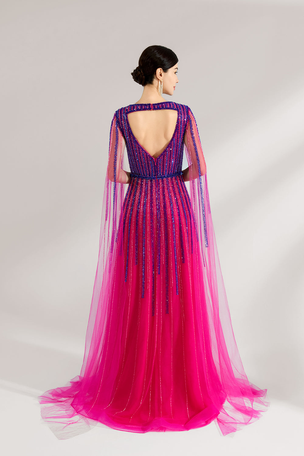 Illuminated softly, a woman enchants in a pink - purple gradient gown. With sequin detailing, a cut - out neckline, and a tulle cape, it creates a magical and elegant look for formal events.2