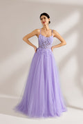Set against a light backdrop, a woman wears a lavender tulle gown. It has thin straps, a sweetheart neckline with intricate lace embroidery on the bodice, and a flowing tulle skirt. The graceful design gives off a romantic and ethereal vibe, ideal for formal occasions such as proms or weddings.1