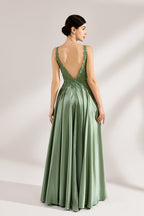 A woman with an elegant updo and a poised stance wears a sage - green satin gown. It has thin straps, a lace - detailed, V - neck bodice, and a high side slit. Paired with silver - tone heels, the outfit radiates grace, perfect for formal events like galas or weddings.5