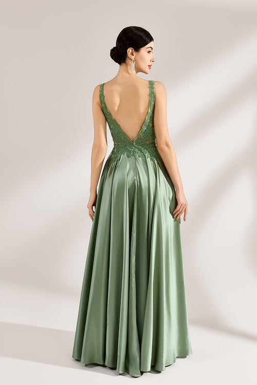 A woman with an elegant updo and a poised stance wears a sage - green satin gown. It has thin straps, a lace - detailed, V - neck bodice, and a high side slit. Paired with silver - tone heels, the outfit radiates grace, perfect for formal events like galas or weddings.5