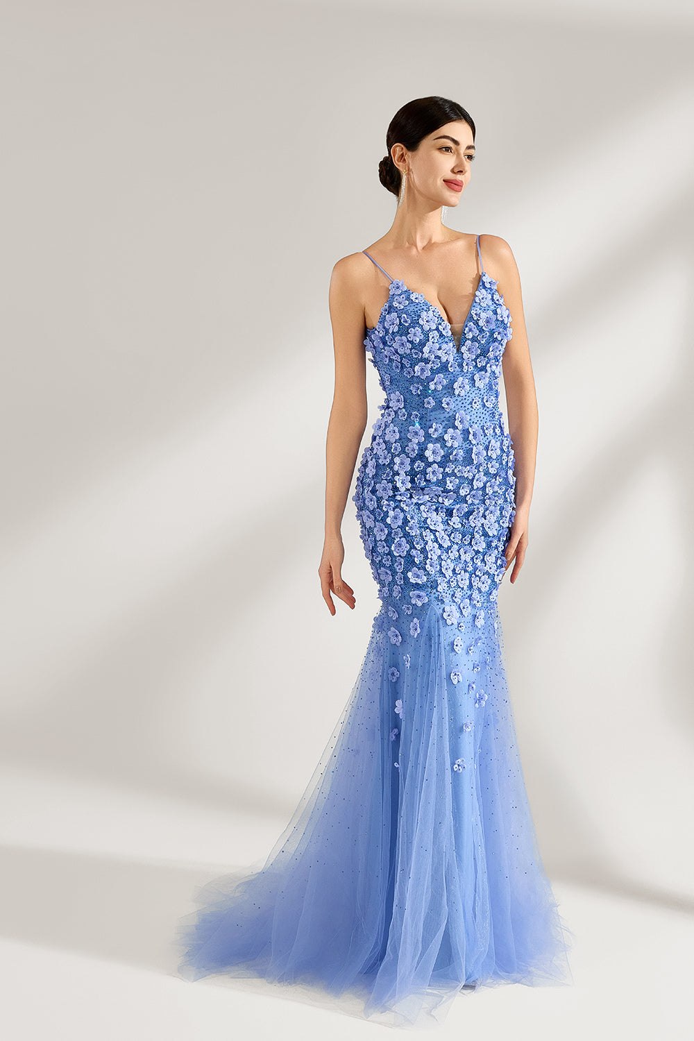 A woman stands against a light background, wearing a light - blue tulle gown. It features thin straps, a deep V - neckline, intricate 3D floral appliqués with sequins on the bodice and skirt, and a mermaid silhouette with a trailing tulle skirt. The elegant design creates a romantic and glamorous look, perfect for formal events like proms or weddings.3