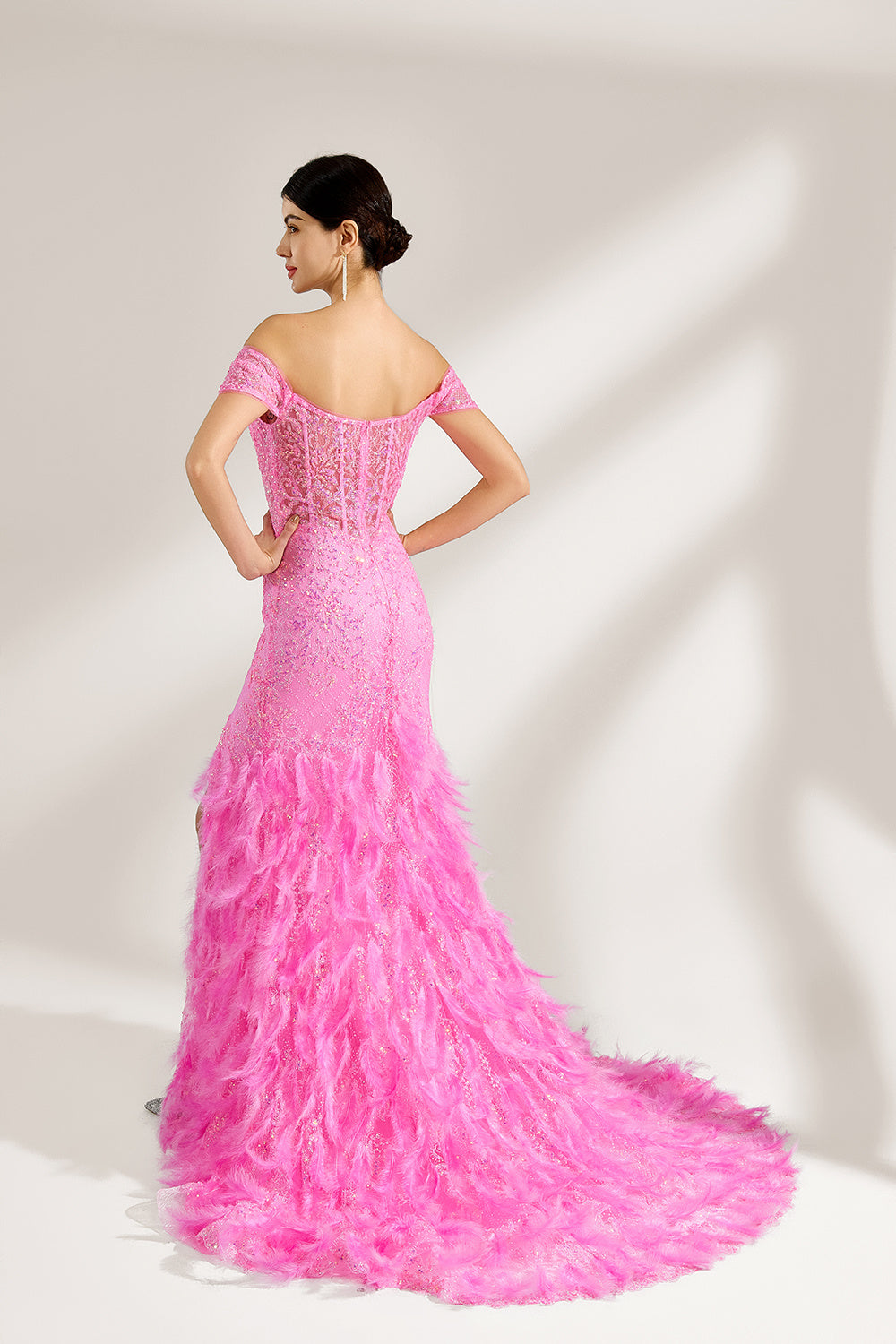 A woman stands against a light background, wearing a pink feather - trimmed gown. It features an off - shoulder neckline, sheer lace panels at the bodice, and a high side slit. The feathered skirt and intricate lace create a glamorous, romantic look, perfect for formal events like galas or weddings, exuding elegance and charm.2