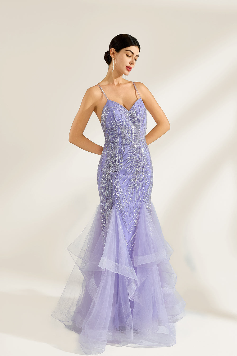 A woman stands against a light background, wearing a lavender mermaid gown. It has thin straps, a deep V - neckline, and is adorned with intricate silver bead patterns. The layered tulle skirt adds a romantic touch, perfect for formal events like galas or weddings, exuding elegance and charm.4
