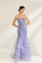 A woman stands against a light background, wearing a lavender mermaid gown. It has thin straps, a deep V - neckline, and is adorned with intricate silver bead patterns. The layered tulle skirt adds a romantic touch, perfect for formal events like galas or weddings, exuding elegance and charm.4