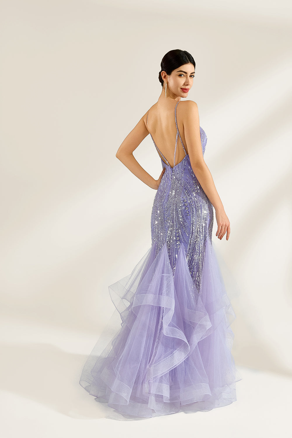 A woman stands against a light background, wearing a lavender mermaid gown. It has thin straps, a deep V - neckline, and is adorned with intricate silver bead patterns. The layered tulle skirt adds a romantic touch, perfect for formal events like galas or weddings, exuding elegance and charm.2
