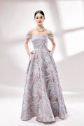 Set against a light backdrop, a woman dons an off - shoulder, light - purple gown with a marble - like pattern. It has short sleeves, a fitted bodice, and a full skirt, along with pockets for practicality. The unique pattern and elegant design make it ideal for formal gatherings, radiating sophistication.1
