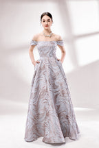 Set against a light backdrop, a woman dons an off - shoulder, light - purple gown with a marble - like pattern. It has short sleeves, a fitted bodice, and a full skirt, along with pockets for practicality. The unique pattern and elegant design make it ideal for formal gatherings, radiating sophistication.1