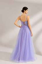 The model has her hair neatly styled and wears long, elegant earrings. The dress is lavender. It features a square neckline with spaghetti straps, and the bodice is adorned with delicate lace. The skirt is made of flowing tulle, creating a dreamy and elegant look, perfect for formal occasions.2