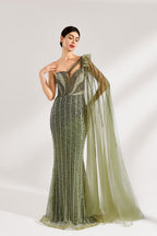 Illuminated softly, a woman captivates in an olive - green one - shoulder evening gown. The sequined mermaid silhouette, paired with a tulle cape, creates a striking and elegant look for formal events.3