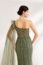 Illuminated softly, a woman captivates in an olive - green one - shoulder evening gown. The sequined mermaid silhouette, paired with a tulle cape, creates a striking and elegant look for formal events.6