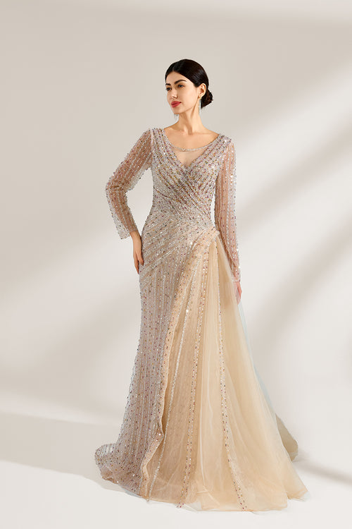 Front view of a luxury champagne gold A-line evening gown featuring a V-neck bodice fully adorned with shimmering hand-beaded embellishments, sheer long sleeves, and a long floor-length skirt with a draped tulle side train, perfect for a wedding, gala, or formal evening event and available for custom bulk orders or wholesale purchase.