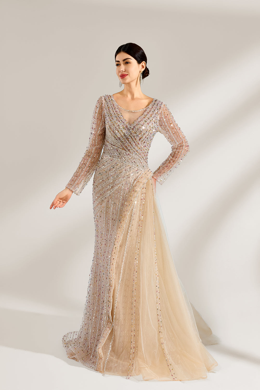 Bathed in soft light, a woman exudes elegance in a light beige sequined evening gown. With long sleeves, a criss - cross V - neck, and tulle - paneled skirt, it creates a glamorous and refined look for formal events.3