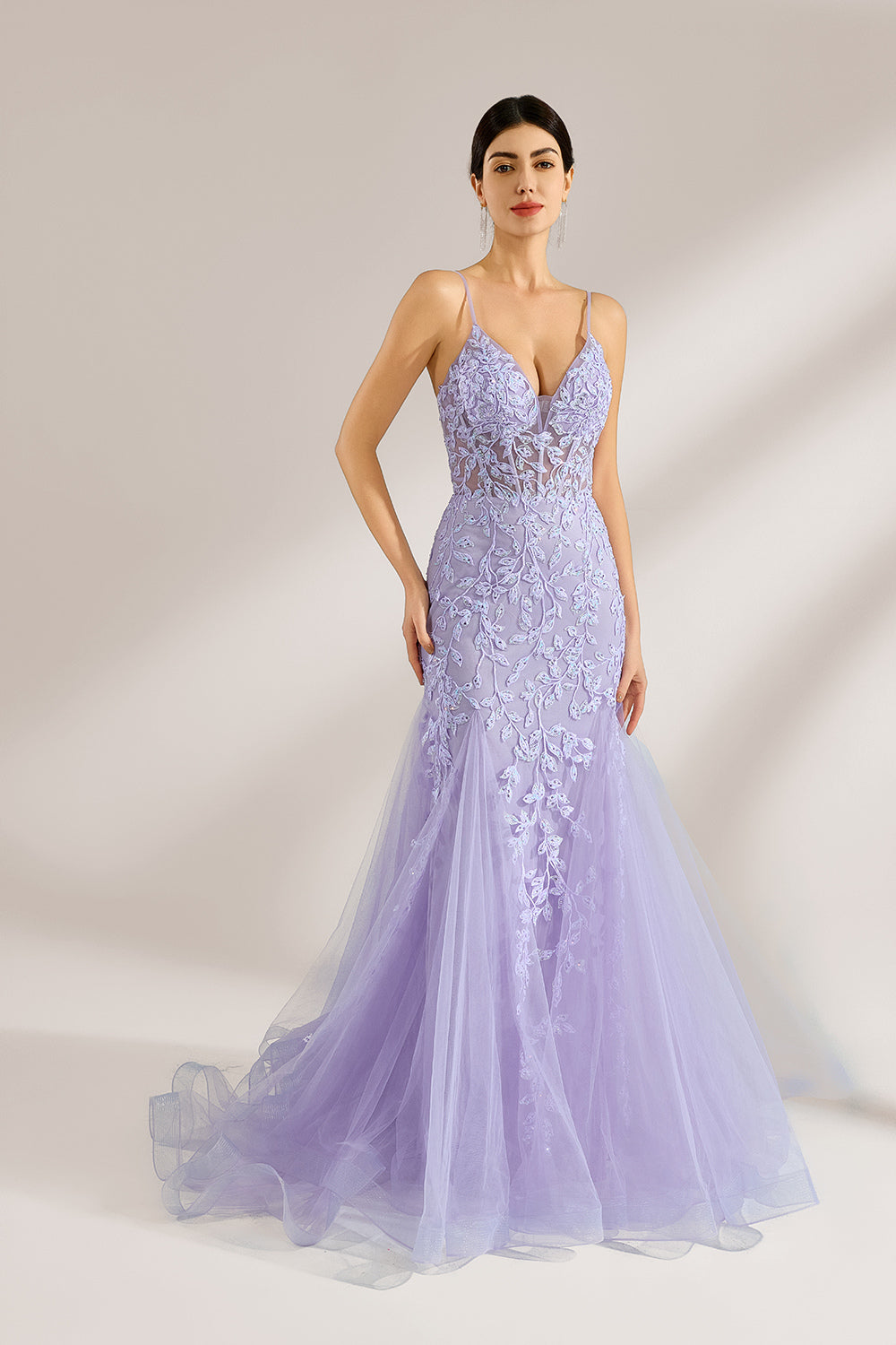 The model sports neatly arranged hair and dangles elegant long earrings. The gown is lavender, featuring a deep V - neckline and slender spaghetti straps. Intricate floral lace embellishes it, and the mermaid - cut skirt, crafted from airy tulle, exudes an elegant and dreamy charm, ideal for formal events.1